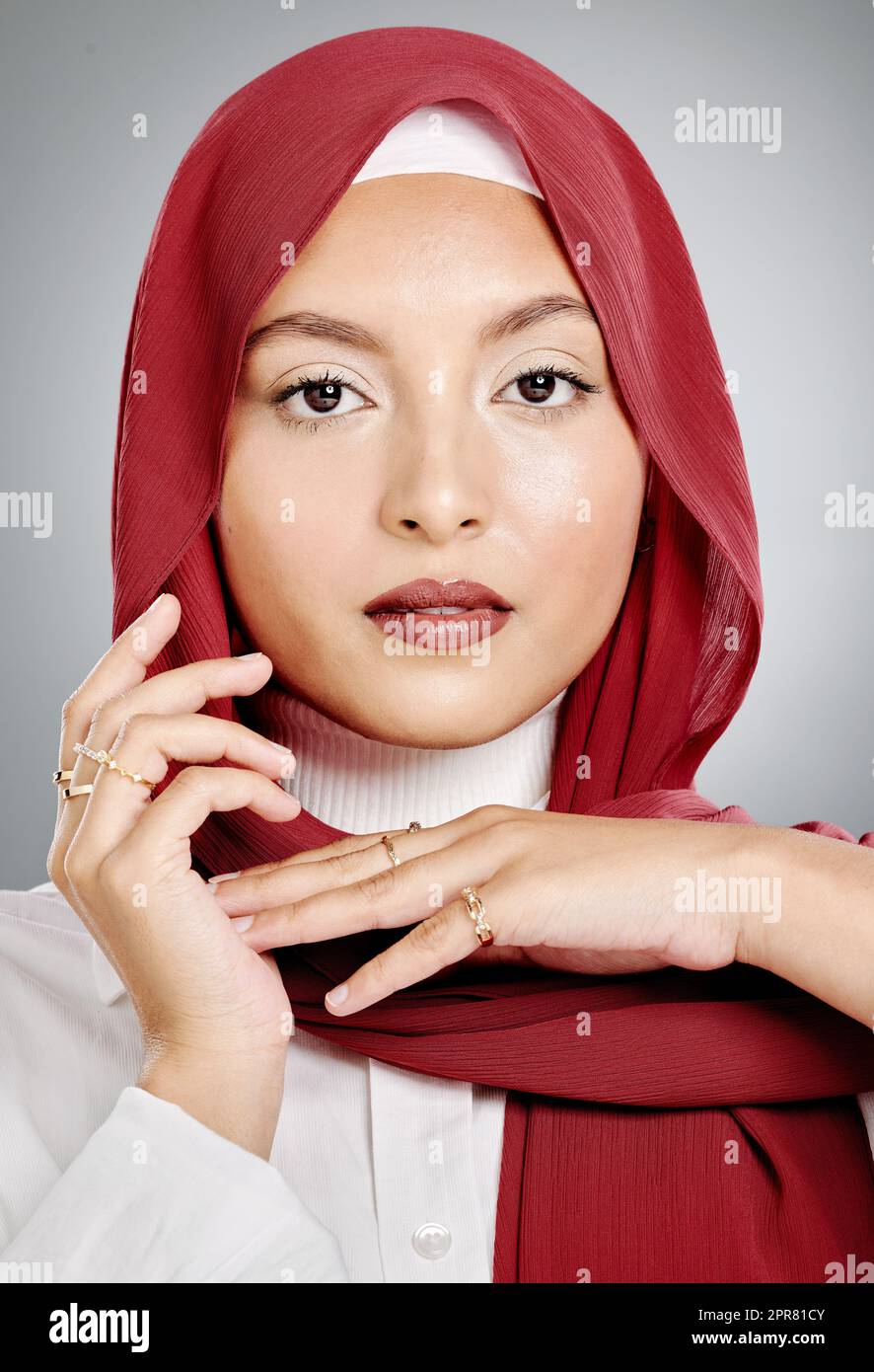 Closeup portrait of a stylish muslim woman posing in a studio with a hijab. Headshot of a stunning confident arab model isolated against a grey background. Zoomed in on fashionable middle eastern Stock Photo