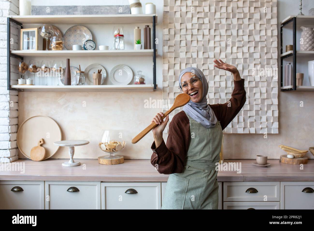 Arab young woman housewife in hijab and apron at home in the kitchen