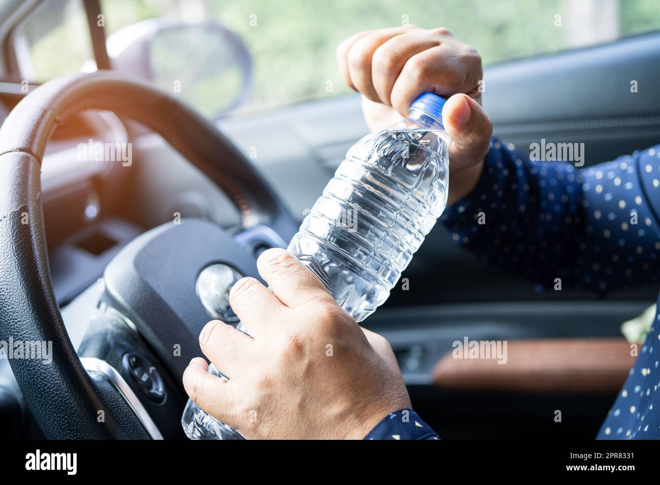 Asian woman driver holding bottle for drink water while driving a car