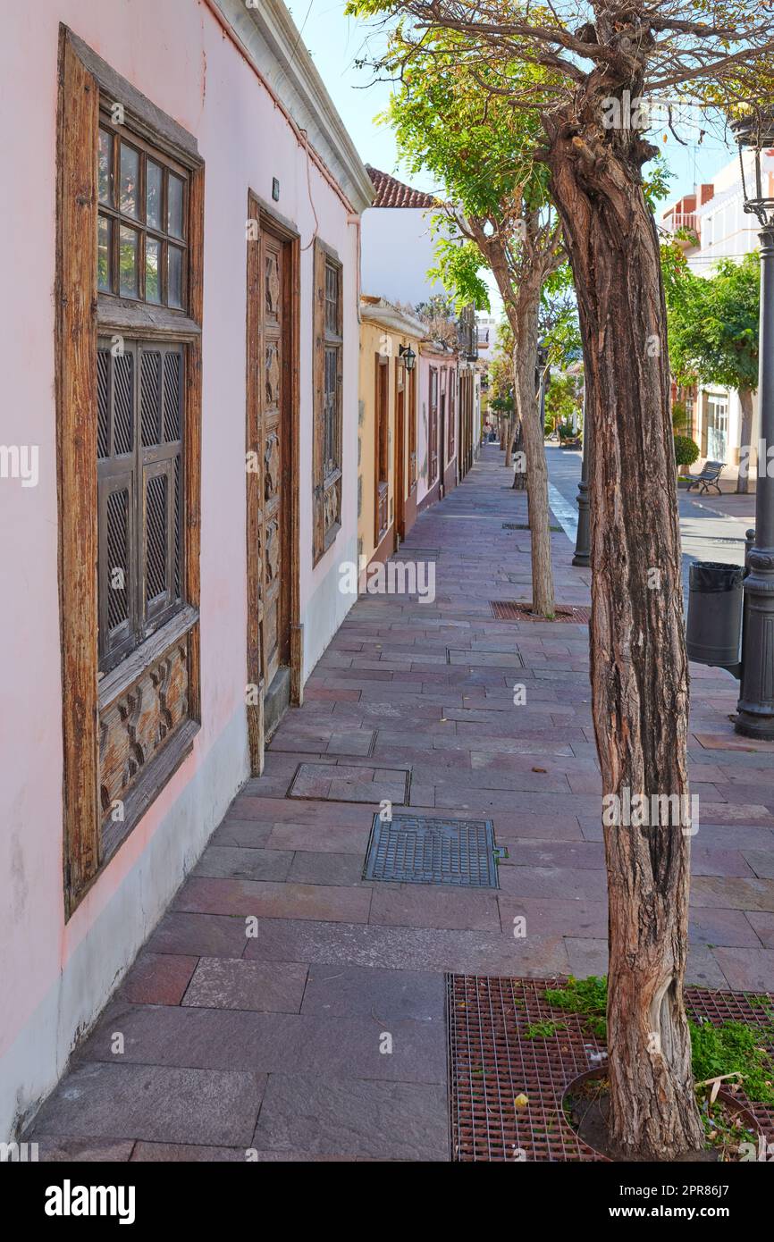 City view paved sidewalk with trees and residential houses or buildings on a quiet street in Santa Cruz, La Palma, Spain. Historical spanish and colonial architecture and famous tourism destination Stock Photo