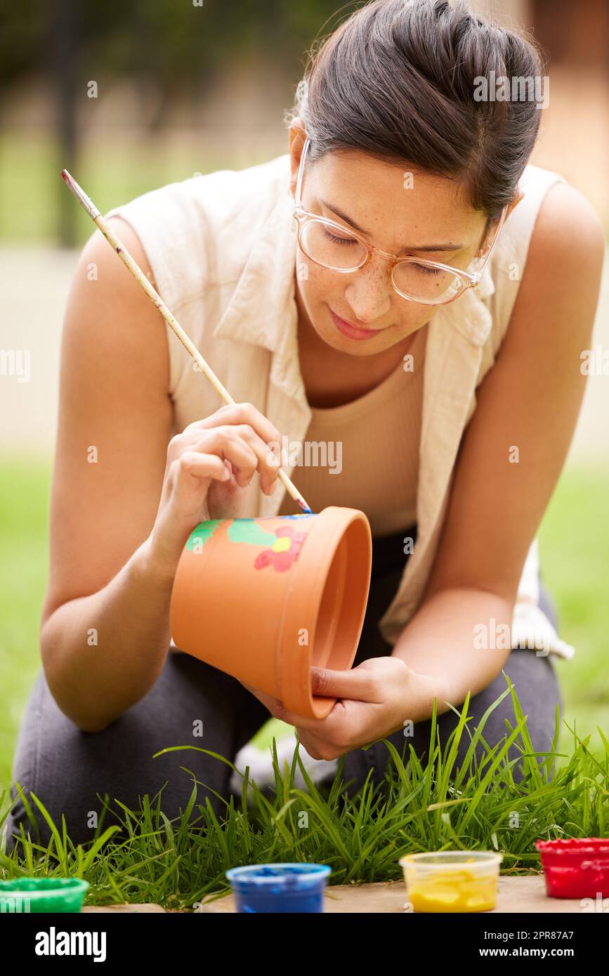 Creativity is seeing something that doesnt exist already. s young woman painting a pot in the garden at home. Stock Photo