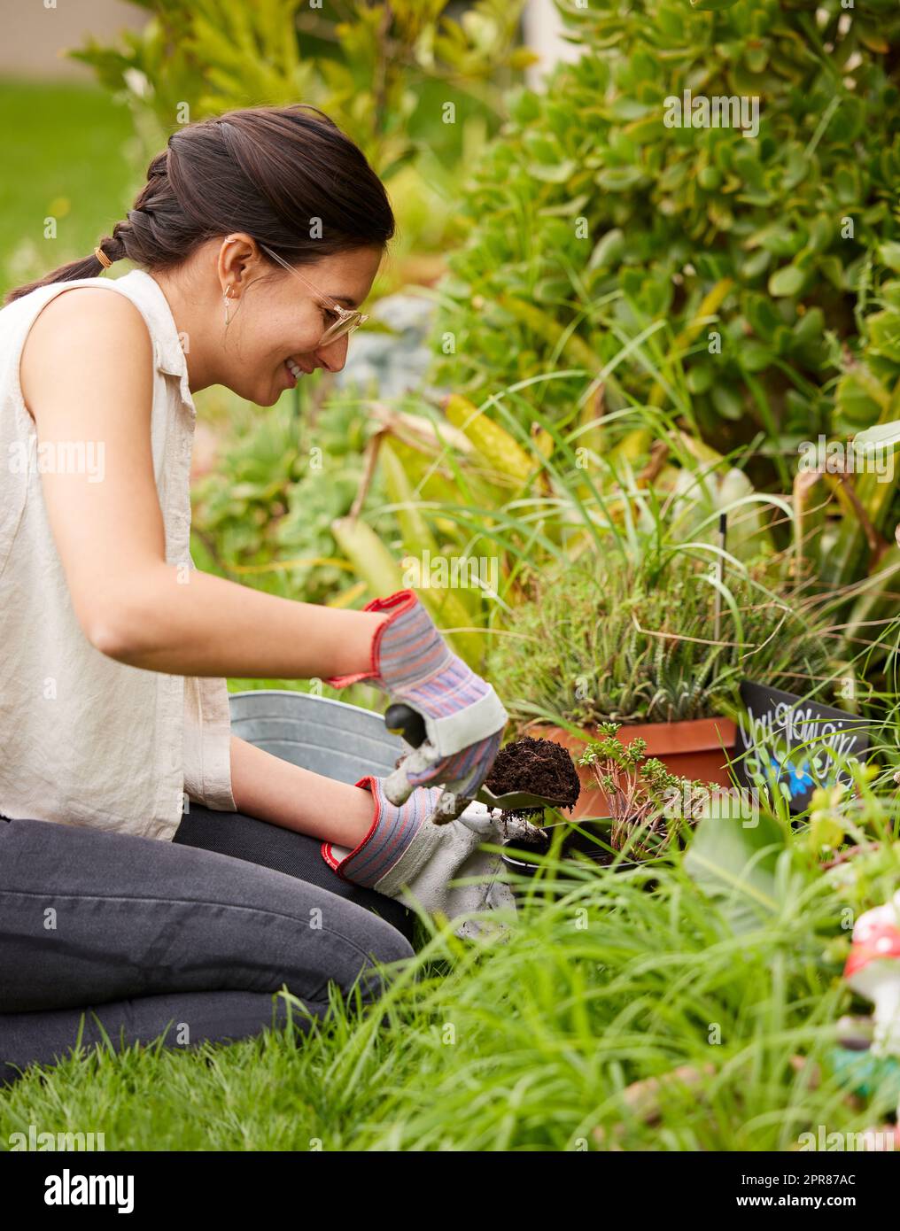 Make hay while the sun shines. an attractive young woman digging with a trowel while doing some gardening at home. Stock Photo
