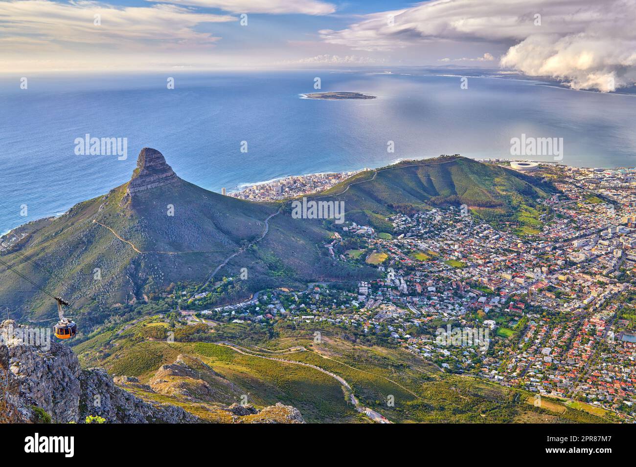 Aerial view of Lions Head mountain with the ocean and a cloudy sky copy space. Beautiful landscape of green mountains with vegetation surrounding an urban city in Cape Town, South Africa Stock Photo