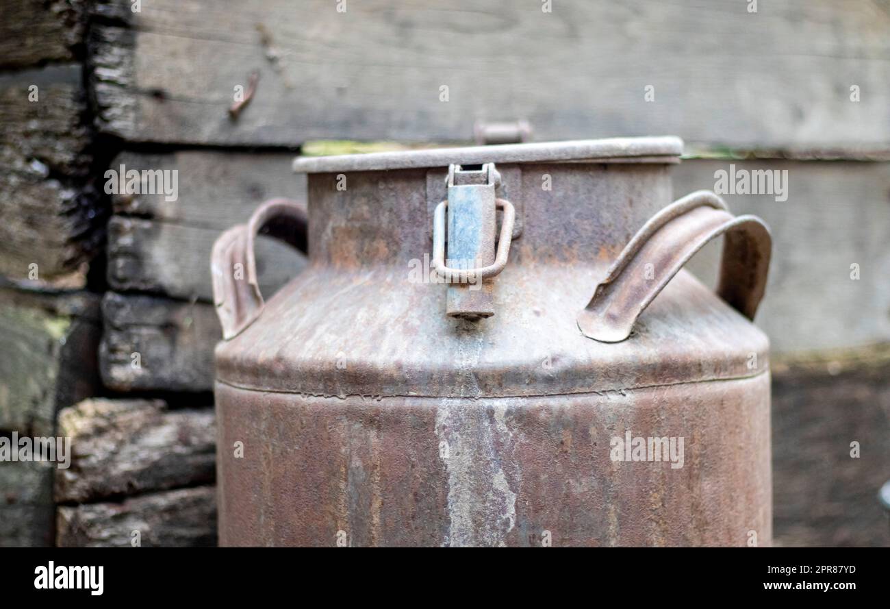 One old rusty metal can in the countryside. Container for transporting liquids, milk or liquid fuels with multiple handles. Milk bank of a cylindrical form with a wide mouth. Bottle with sealed cap. Stock Photo