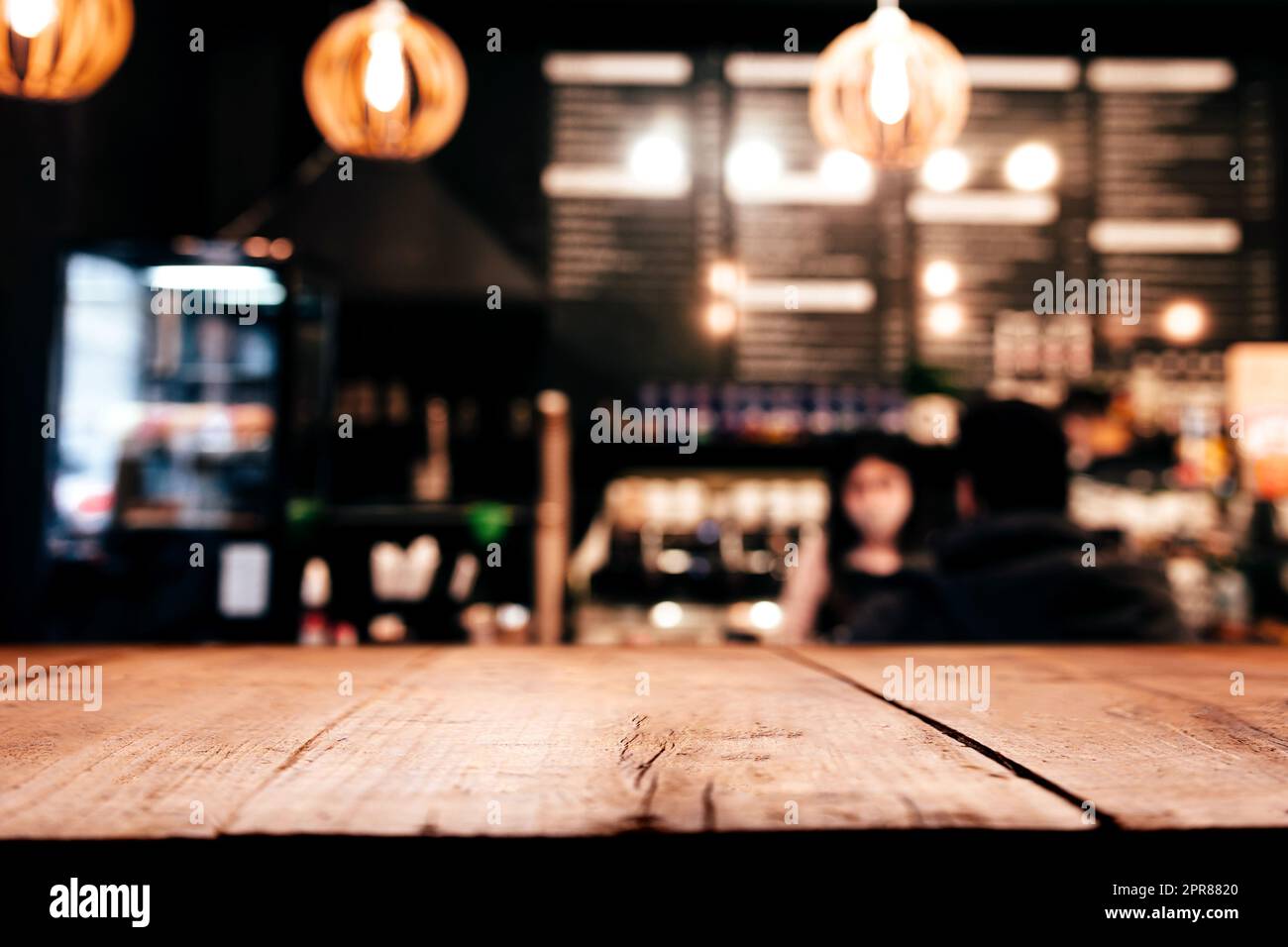 Background with wooden old deck table in front of blurred in bar or restaurant Stock Photo