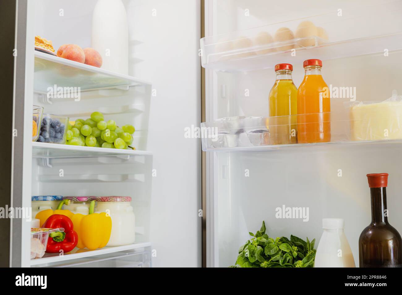 Open fridge or refrigerator door filled with fresh fruits and vegetables Stock Photo