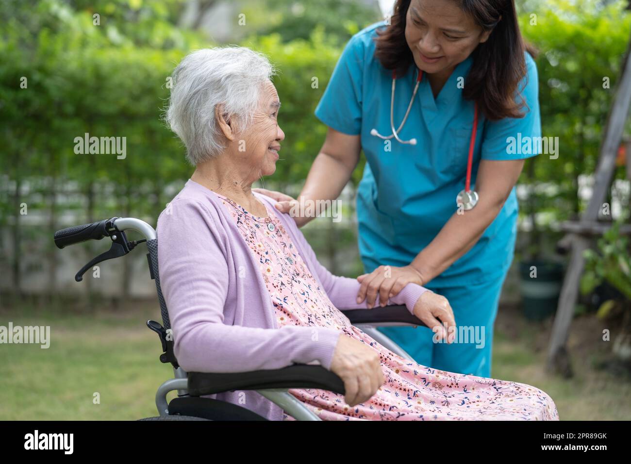 Doctor caregiver help and care Asian senior or elderly old lady woman patient sitting on wheelchair at nursing hospital ward, healthy strong medical concept Stock Photo