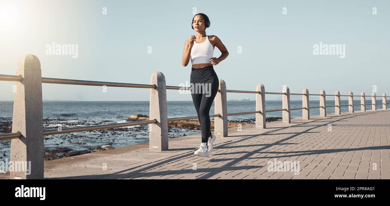 Fit young female athlete in sportswear wearing wireless headphones and