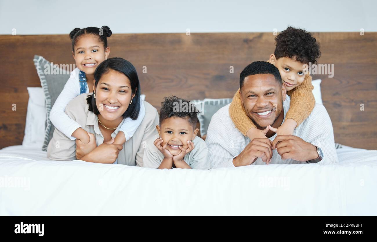 The man of our house is quite little. Portrait of a beautiful young family talking and bonding in bed together. Stock Photo