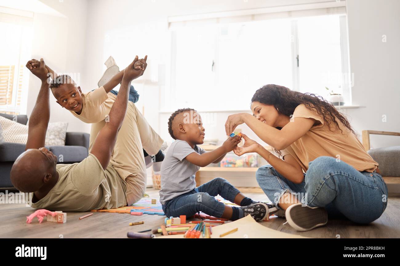 Happiest is the home with a whole lot of fun. a happy young family playing together on the floor at home. Stock Photo