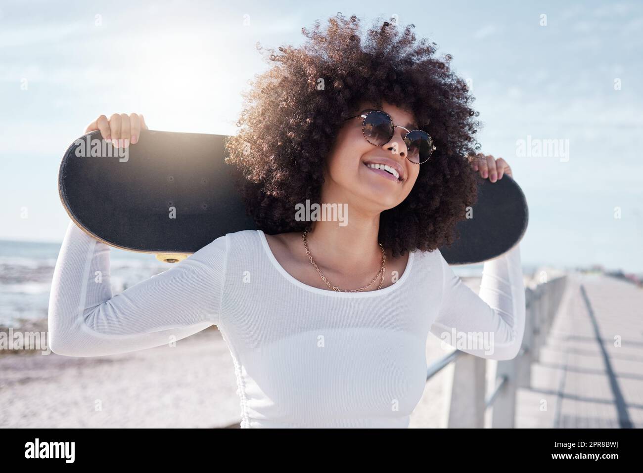 Let the good times roll. a young woman hanging out at the promenade with her skateboard. Stock Photo