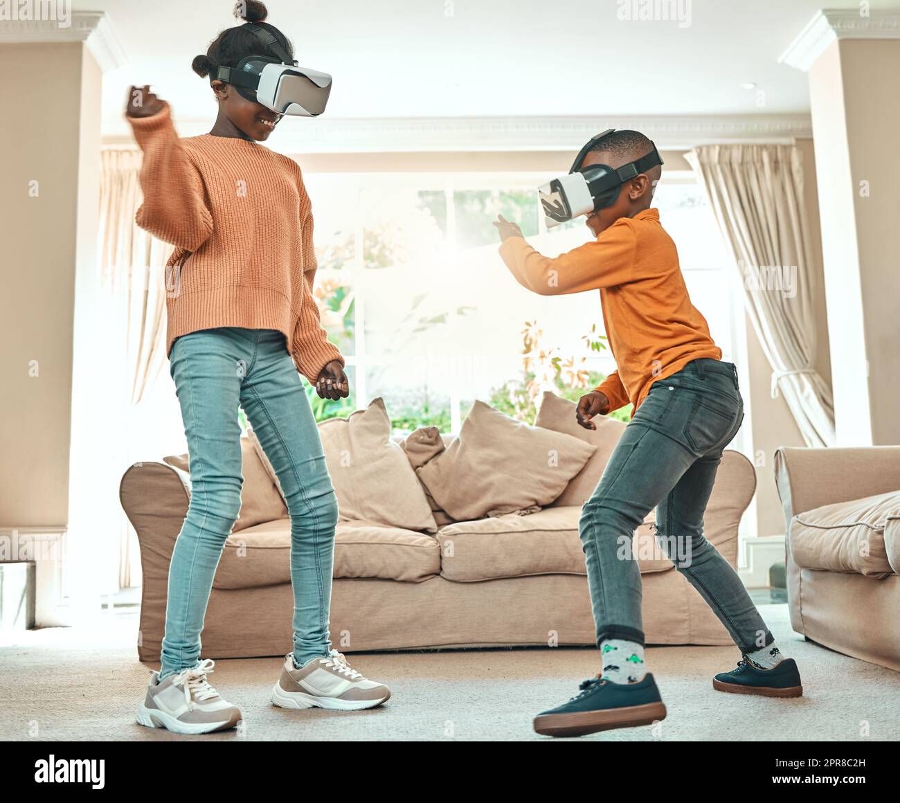 Theyre so entertained by technology. a brother and sister playing with each other while wearing VR headsets at home. Stock Photo