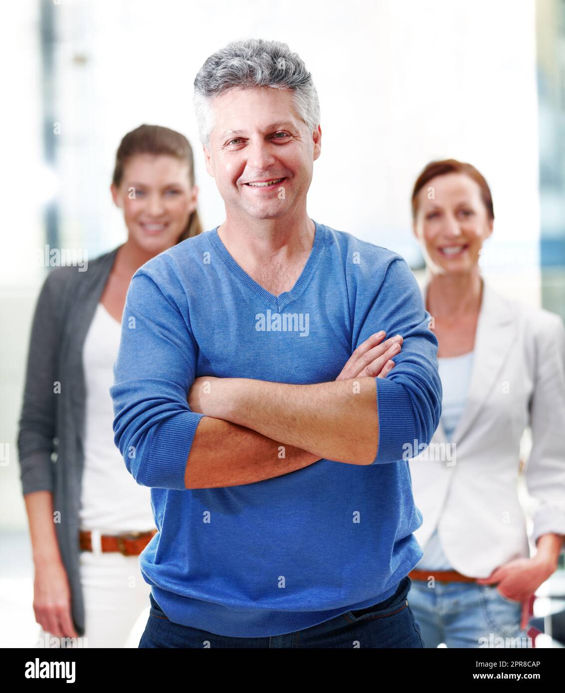 Expert in the field. Portrait of a mature businessman standing confidently with his co-workers behind him. Stock Photo