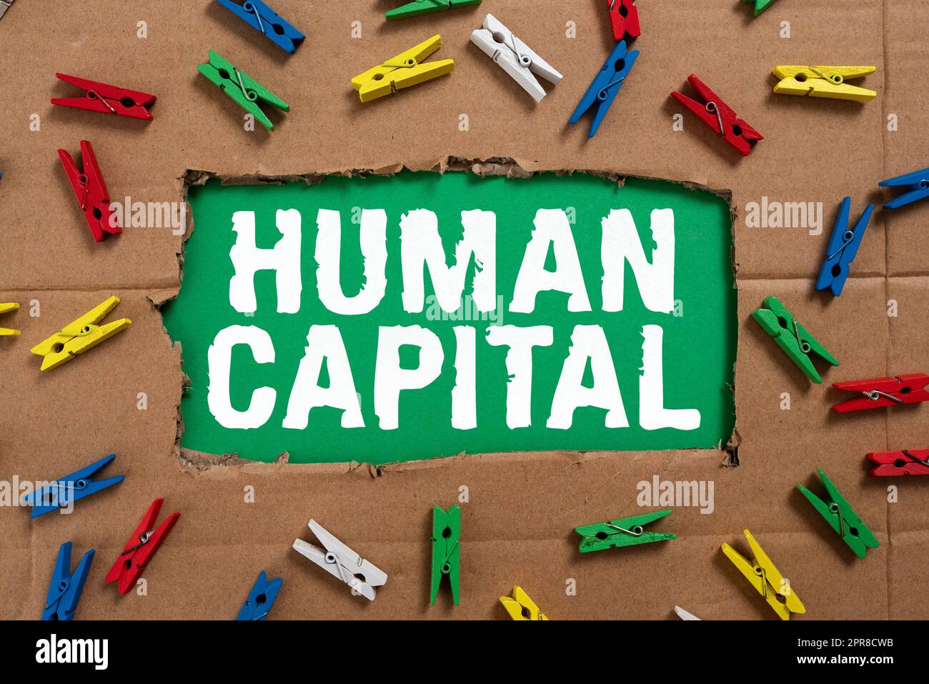 Inspiration showing sign Human Capital. Business approach Intangible Collective Resources Competence Capital Education Important Ideas Written Under Ripped Cardboard With Colored Pegs Around. Stock Photo