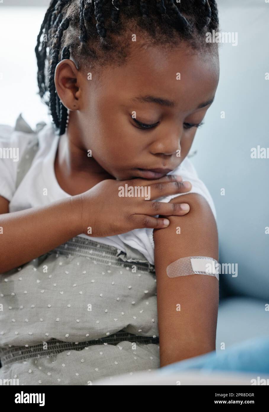 Vaccinate to protect your child against many dangerous diseases. Shot of an adorable little girl with a plaster on her arm after an injection. Stock Photo