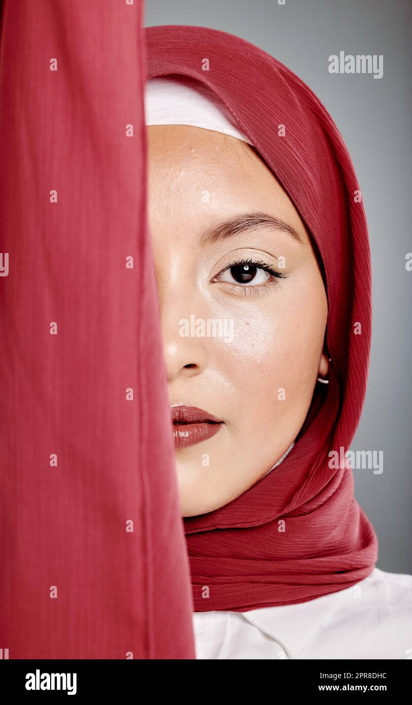 Closeup portrait of elegant muslim woman wearing a hijab, posing in studio. Half headshot of stunning confident arab model isolated against grey background. Zoomed in on fashionable middle eastern Stock Photo