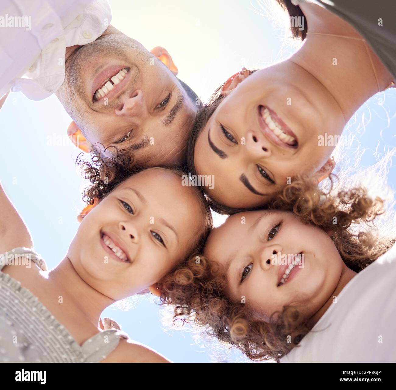 Our circle of love, support and strength. Low angle portrait of a happy young family huddled together on a fun day outdoors. Stock Photo