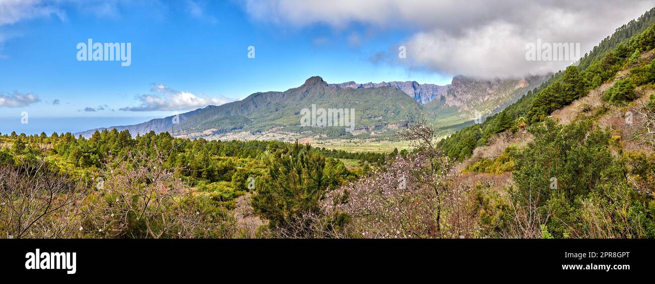 Scenic landscape of mountains in La Palma, Canary Islands, Spain against a cloudy blue sky background with copyspace. Wild plants and shrubs growing on a rocky hill and cliff in natural environment Stock Photo