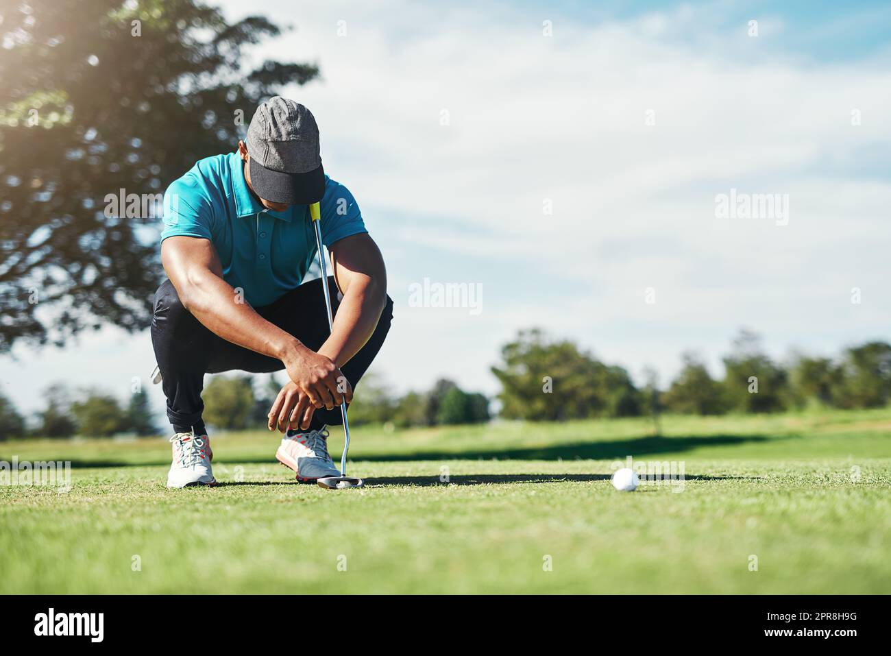 That was so close. a focused young male golfer looking at the ground while being seated on the grass outside during the day. Stock Photo