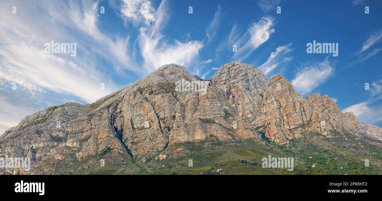 Landscape view of a mountainside with copy space and blue sky background from a lush, green botanical garden or national park. Low angle of rough, rocky, or dangerous terrain in a remote location Stock Photo