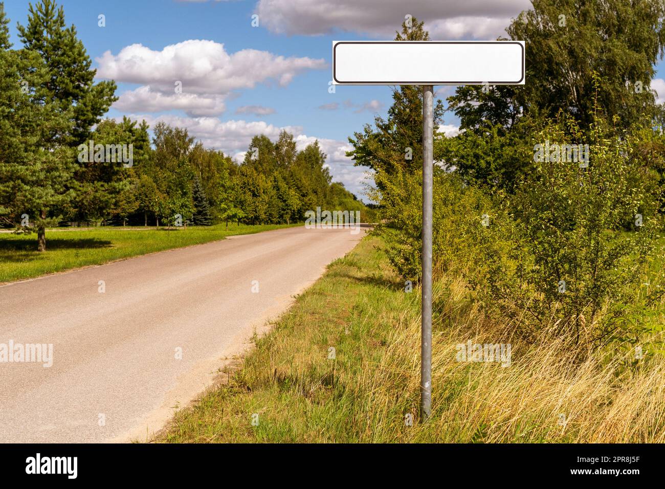 Road with white empty signpost on roadside Stock Photo