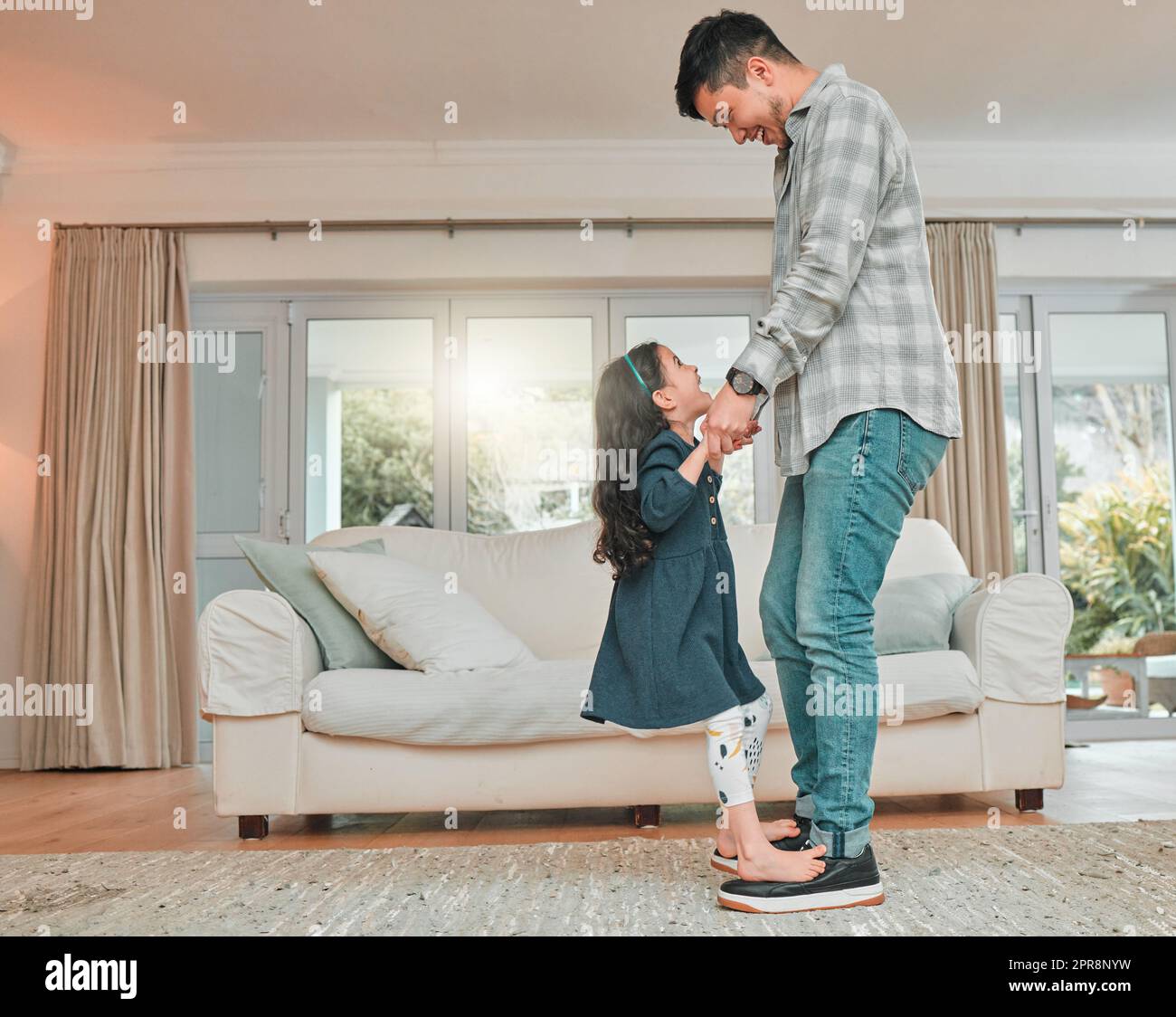 An invested dad is the greatest dad. a father practicing a dance routine with his daughter at home. Stock Photo