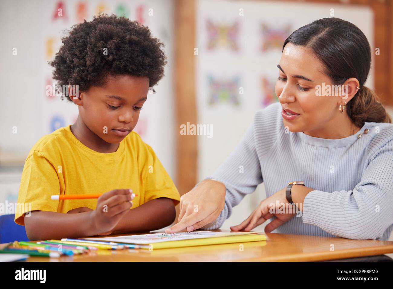 I love the colours youve used here. a female teacher assisting a preschool learner in her class. Stock Photo