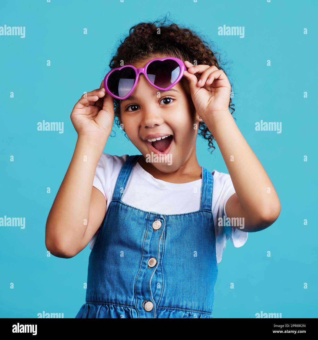 Dont I look cool. an adorable little girl posing against a blue background. Stock Photo
