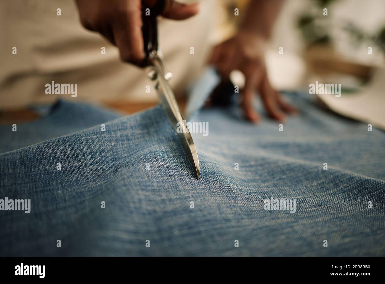 Closeup of hand of fashion designer using a scissor to cut a fabric