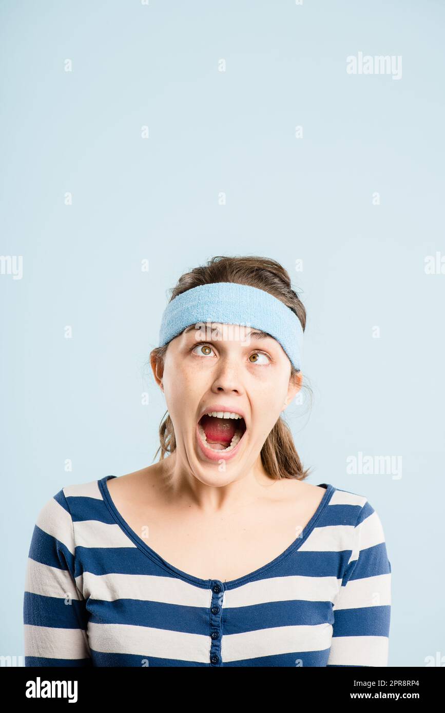 Im about to snap. an attractive young woman standing alone in the studio and pulling funny faces while wearing a headband. Stock Photo