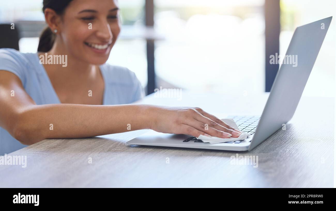 Daily care for every item. a beautiful young woman carefully cleaning a laptop at home. Stock Photo