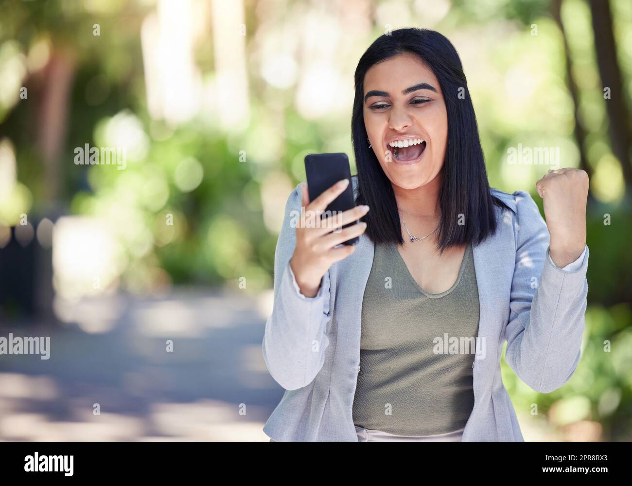 Luck is on my side today. a young businesswoman cheering while using a cellphone outdoors. Stock Photo