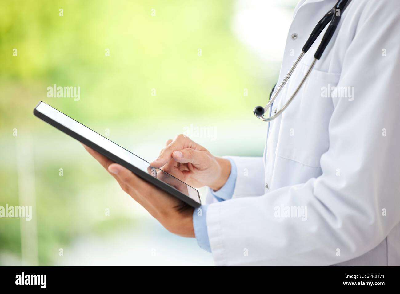 Closeup of female doctor working on her digital tablet in the office. A unknown mixed race and professional young woman working in a hospital office. Health resources are easy to find online Stock Photo