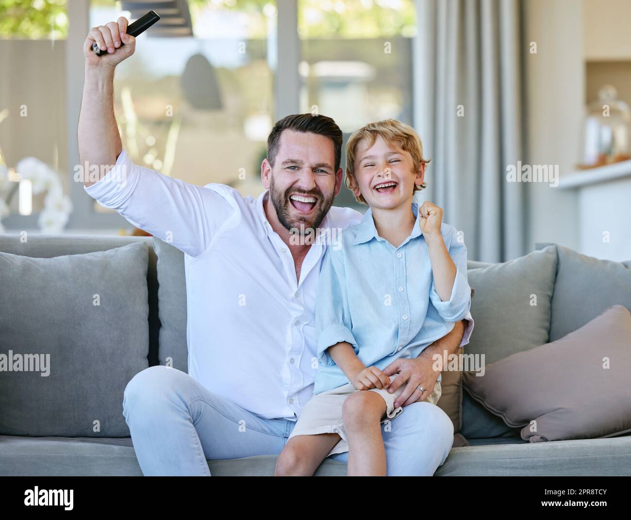 Cheering on their favourite team. Cropped portrait of a handsome mature man and his son cheering while watching TV in the living room at home. Stock Photo