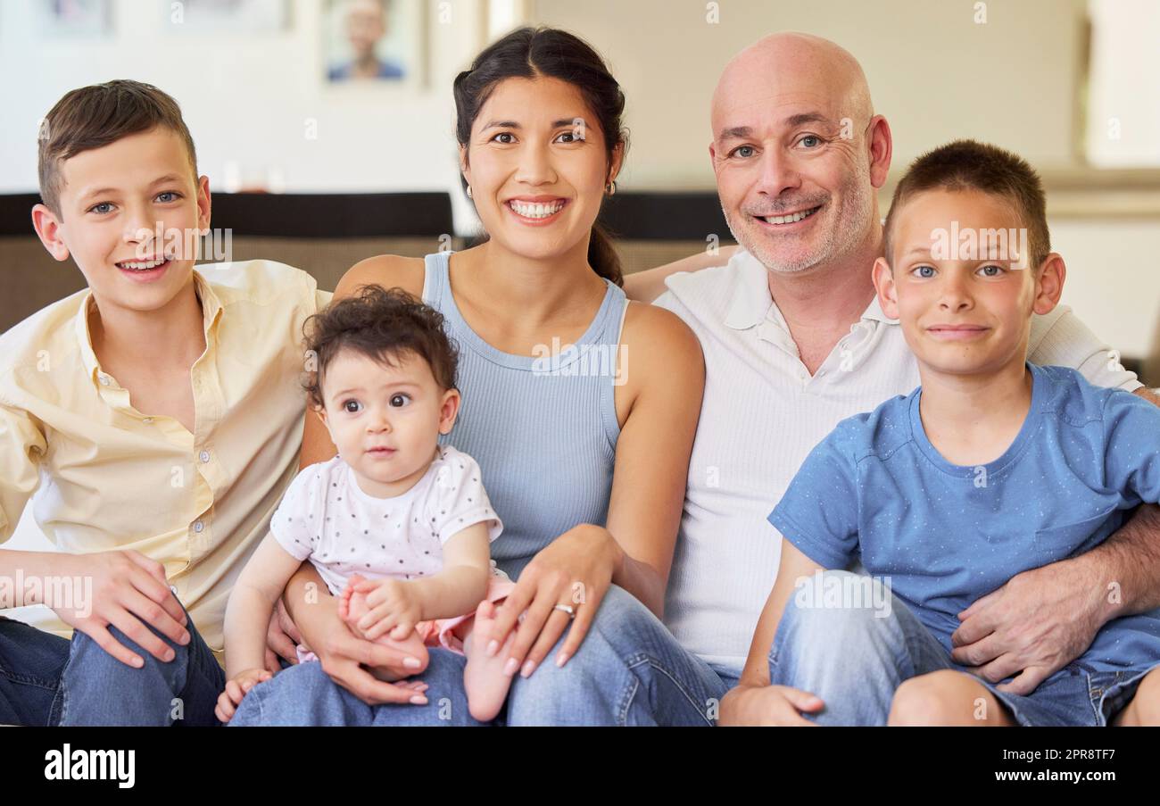 Happy interracial family bonding and relaxing together at home. Brothers and their sister sitting with their caucasian father and mixed race mother. Man and woman spending time with their children Stock Photo