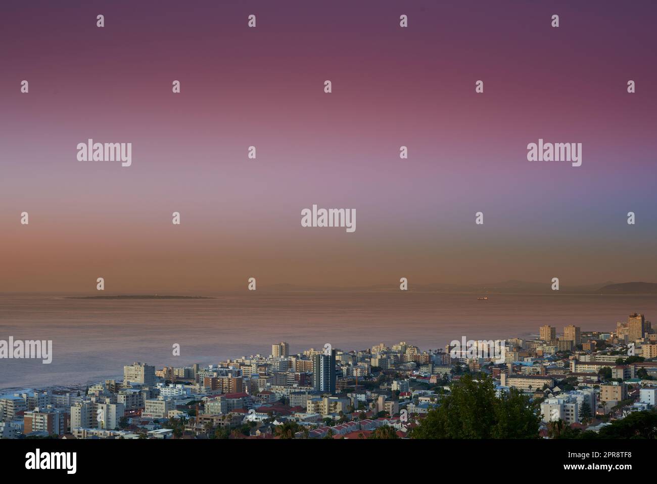 Copy space sunset sky and city view of building infrastructure with sea or ocean background in abroad travel destination. Aerial of Cape Town downtown centre and urban cityscape architecture at night Stock Photo