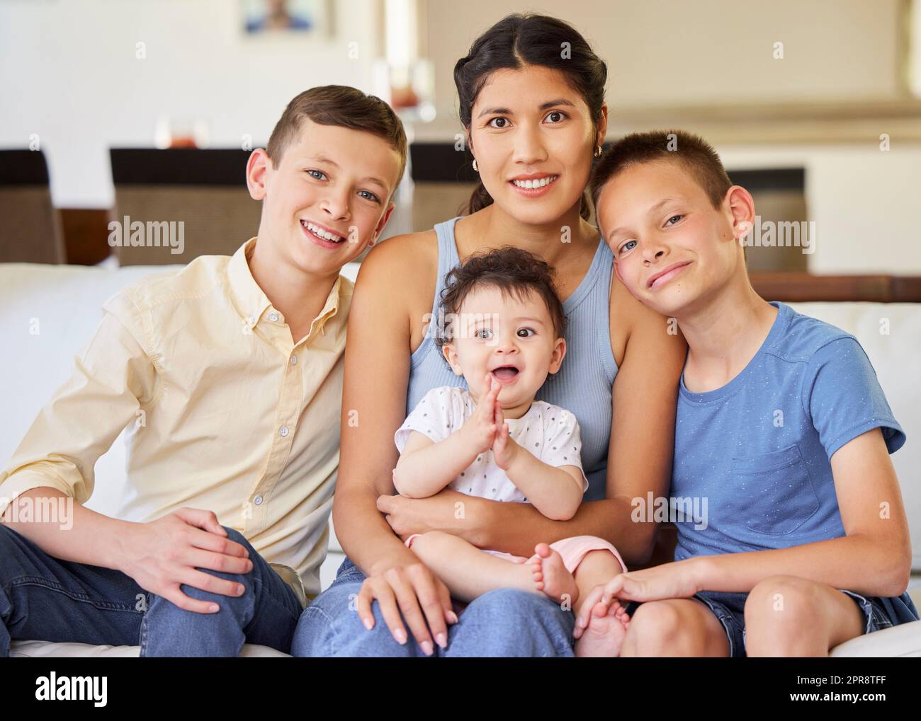 Portrait of a multiracial family at home.Mother with her adoptive sons. Young mother relaxing with her children. Mixed race family relaxing together at home. Boys spending time with their parent. Stock Photo