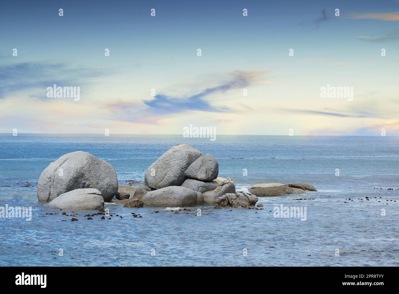 Copyspace at sea with a cloudy blue sky background and rocky coast in Western Cape South Africa. View of calm scenic sea landscape with rocks. Stunning destination for a summer holiday background Stock Photo