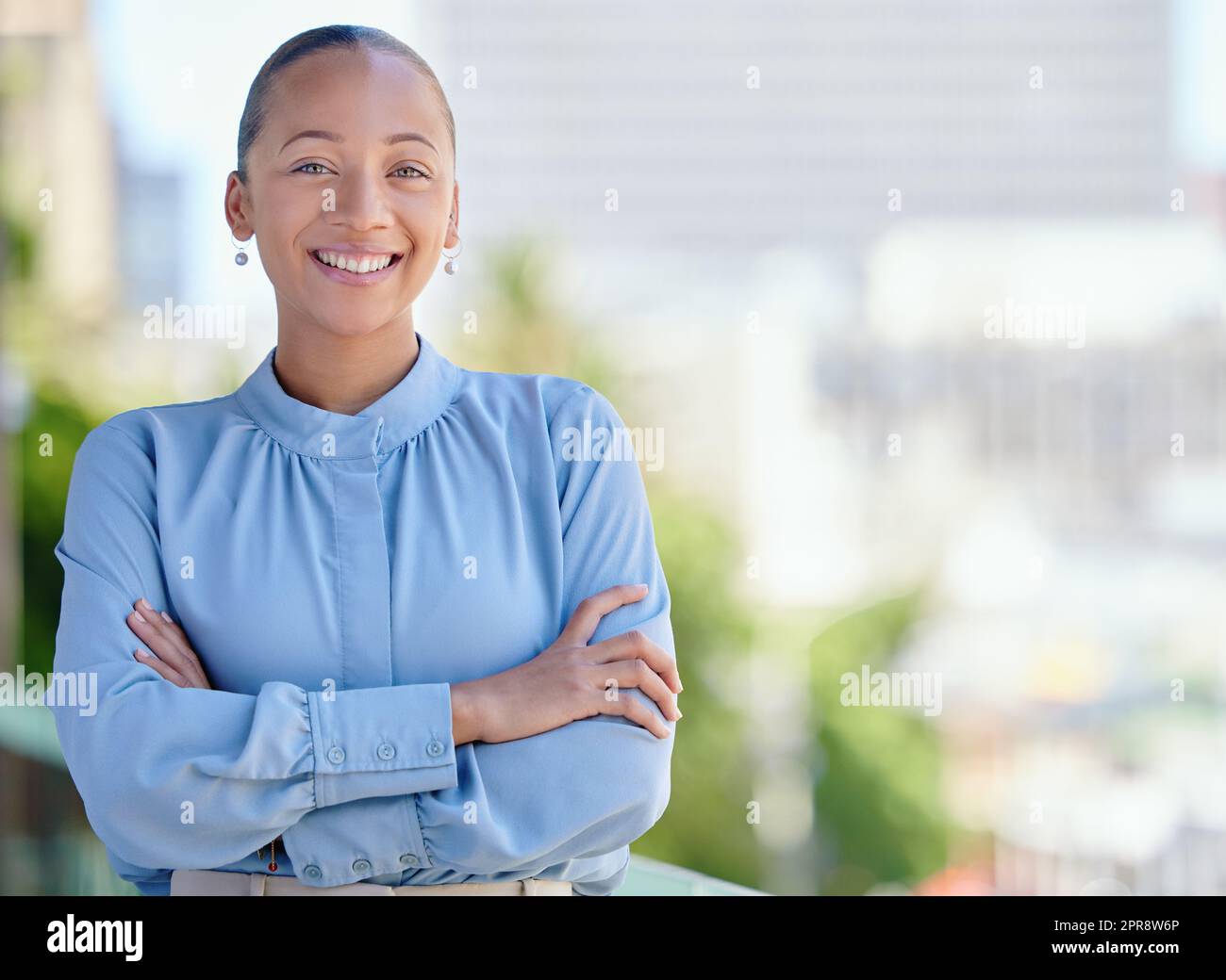 Happy, confident and smiling business woman standing with arms crossed outside at work alone. Portrait of the face of one cheerful, joyful and proud female corporate professional with arms folded Stock Photo