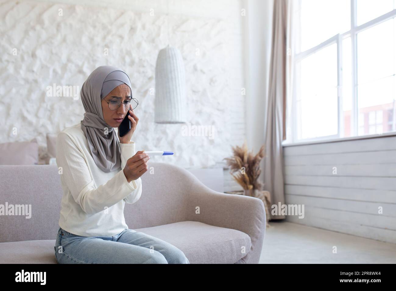 Upset and disappointed young arab woman in hijab sitting on sofa at ...