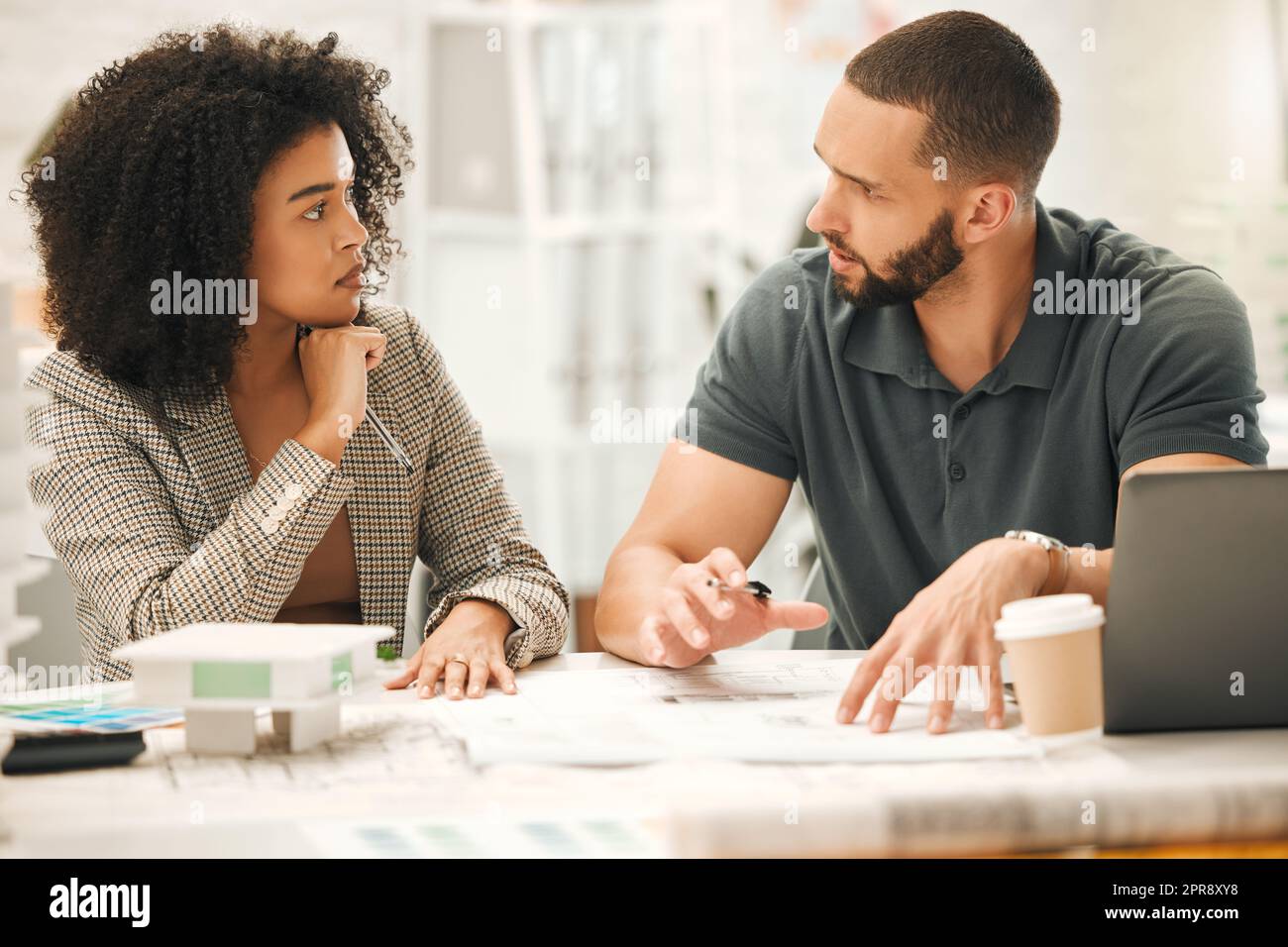 Focused colleagues working on a project together. Young architects working together in an office. Businesspeople working in a design agency. Professional creatives brainstorm and collaborate. Stock Photo