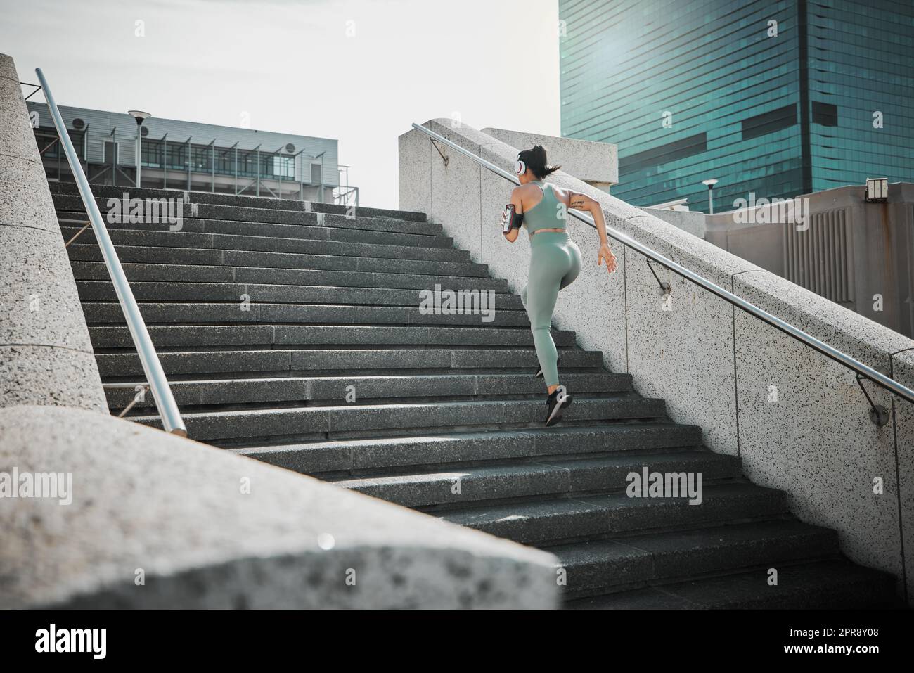 Fitness. Woman Doing Workout Exercise On Street. Beautiful Fit Girl Wearing  Fitness Tracker, Headphones And Armband Phone Case Stretching Her Long Legs  Outdoors. Sports Devices. High Resolution Stock Photo, Picture and Royalty