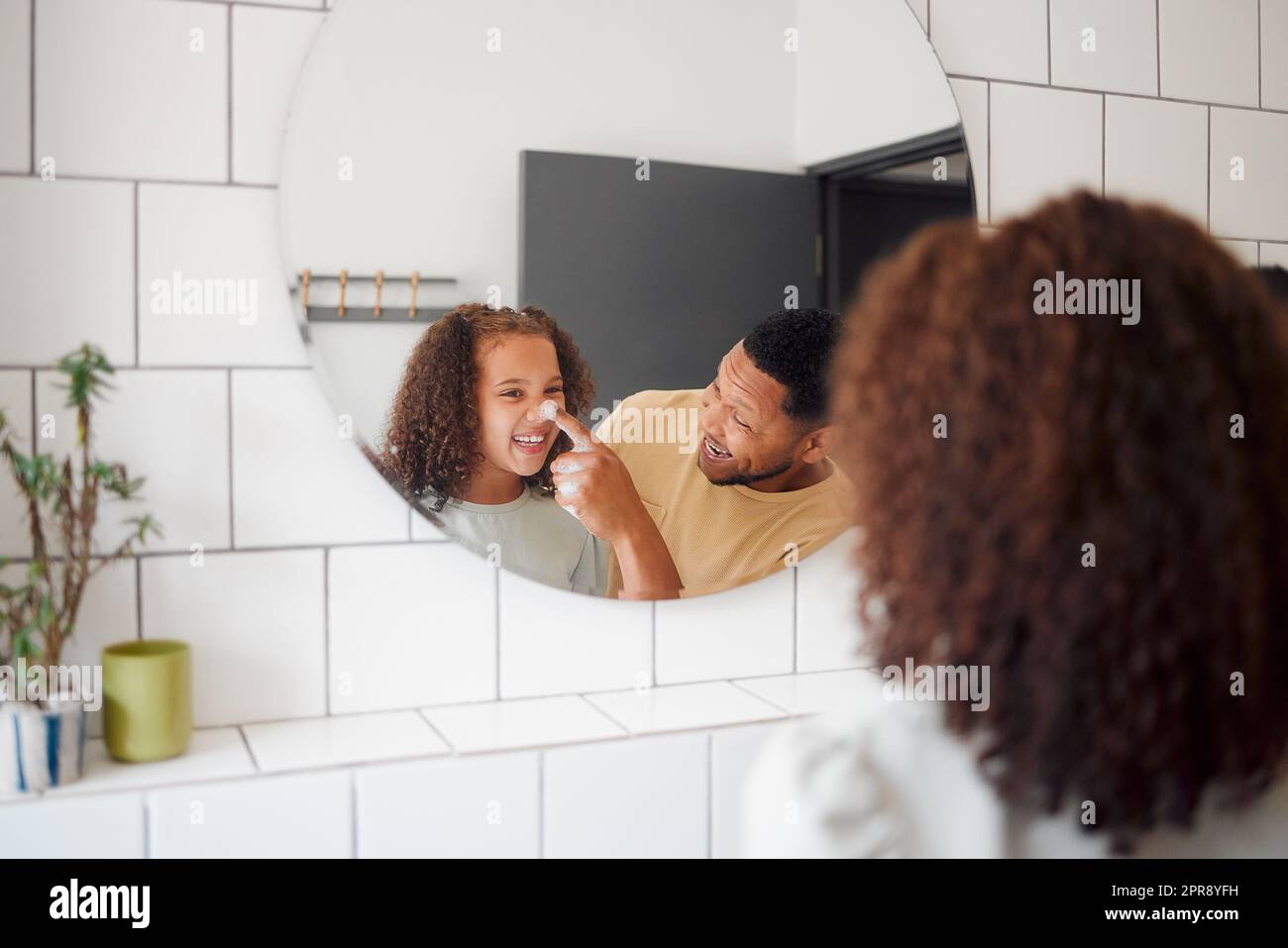 Happy mixed race father and daughter washing their hands together in a bathroom at home. Single African American parent teaching his daughter about hygiene while having fun and being playful Stock Photo