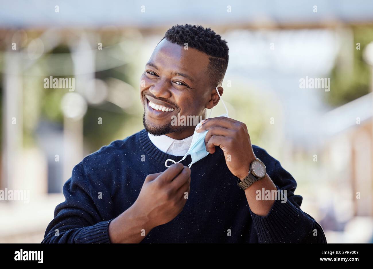 Portrait of a young businessman standing in the street in the city smiling and looking happy on a sunny day. African american male expressing happiness on his face Stock Photo