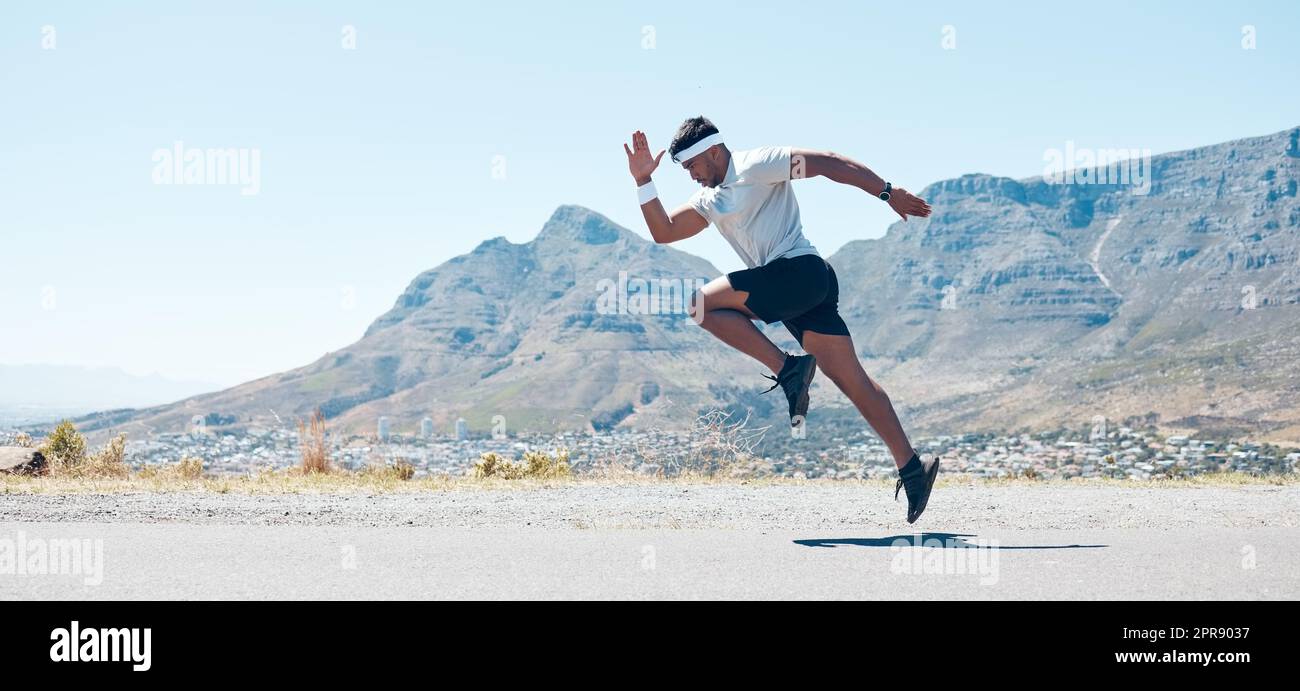 A fit handsome mixed race handsome young man wearing sunglasses running alone outside during the day. Indian male exercising outside during a run in the road outdoors Stock Photo