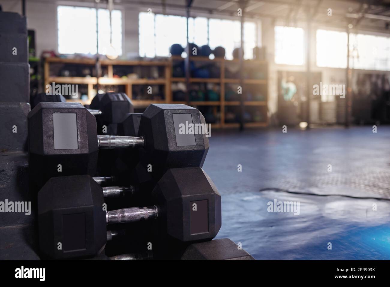Stacked and piled heavy dumbbell weights arranged in empty gym with nobody during day with copyspace. Weightlifting equipment group organised in health and sports centre with no one. Healthy routine Stock Photo