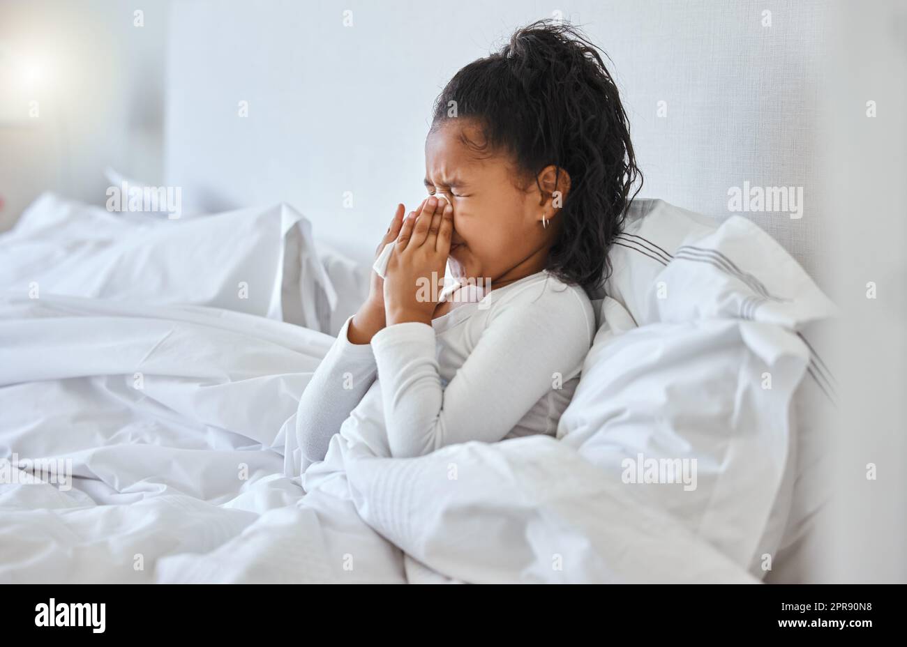 Snotty nose. a little girl blowing her nose and looking sick in bed