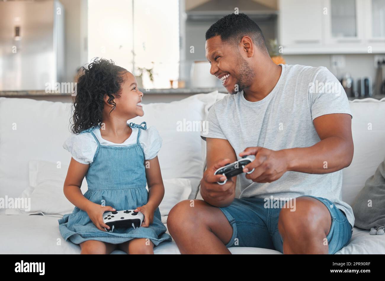 I can beat you dad. a young man playing video games with his daughter at home. Stock Photo