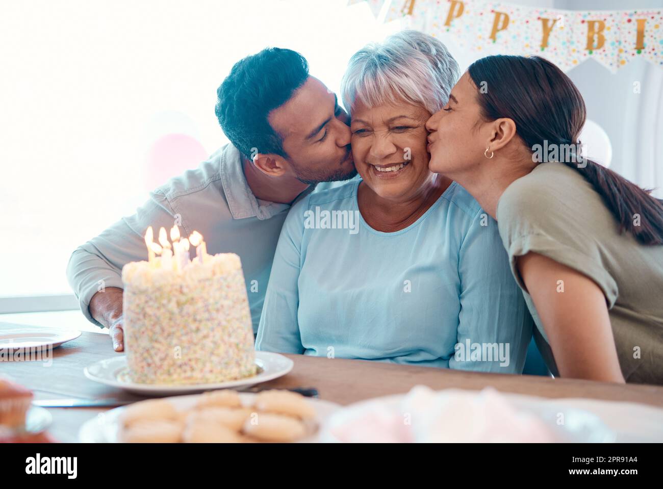 Smooch. two young adults celebrating a birthday with a mature woman at home. Stock Photo
