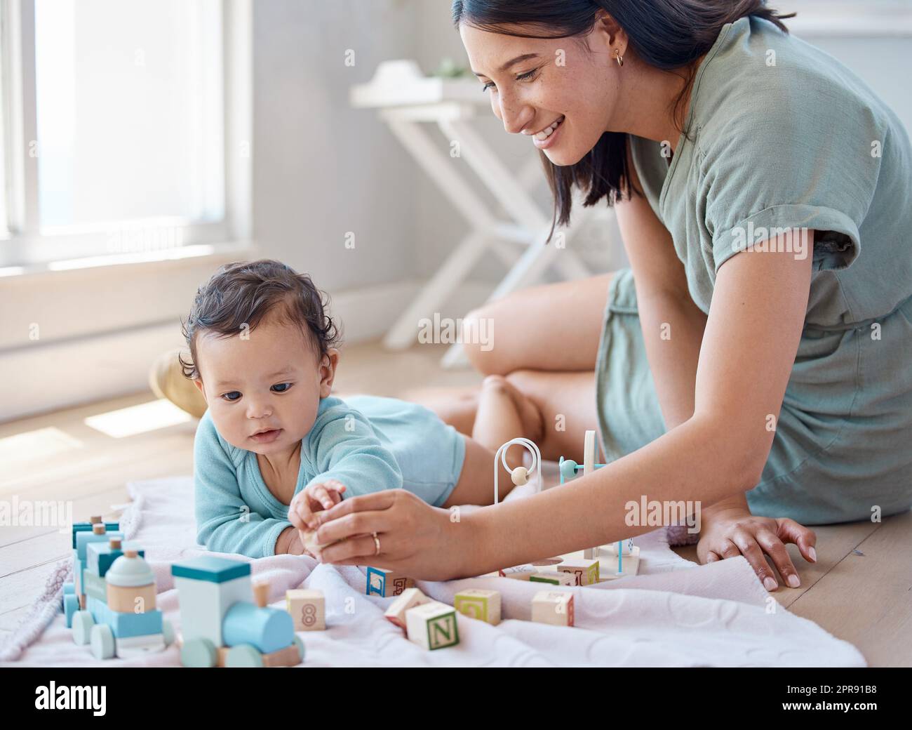 We make tummy time fun. a woman playing with her baby at home. Stock Photo